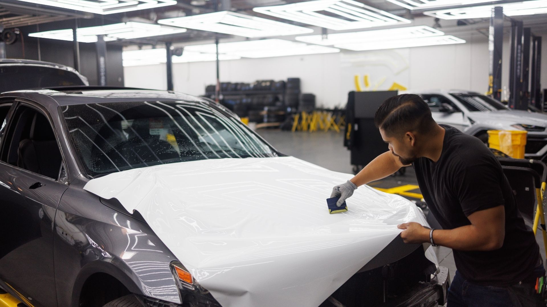 Technician applying vehicle wrap to car hood for commercial wraps service in Stockton, CA